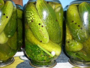 Закрученные банки с огурцами переворачивают на крышки и укутывают пледом
